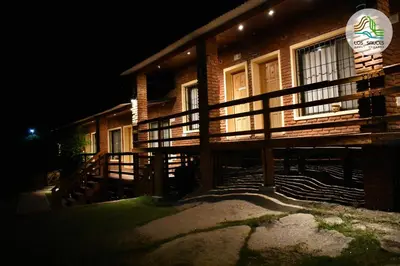 a house at night with a sign in front of it at APART CABAÑAS LOS SAUCES in Tanti