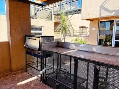 a barbecue grill on a patio with a building at Departamentos Miralejos 6 in Villa Carlos Paz