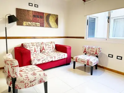 a living room with a red couch and two chairs at Departamentos Miralejos 6 in Villa Carlos Paz