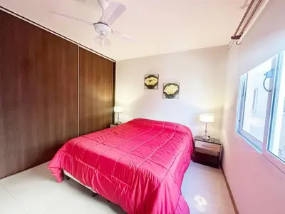 a bedroom with a pink bed and a ceiling fan at Departamentos Miralejos 6 in Villa Carlos Paz