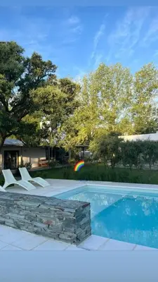 a pool with chairs and a rainbow in a yard at Favre Suites in Mina Clavero