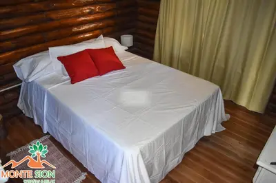 a bed with two red pillows on top of it at Monte Sion cabañas & relax in San Javier