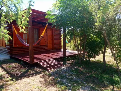 a wooden cabin with a hammock in front of it at Monte Sion cabañas & relax in San Javier