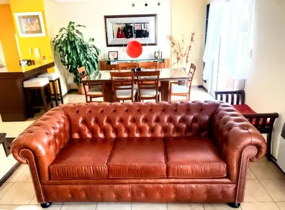 a brown leather couch in a living room with a table at HERMOSO DÚPLEX DE CATEGORÍA COMPLETAMENTE EQUIPADO in Cordoba