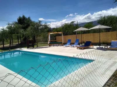 a swimming pool with blue chairs and umbrellas at Cabañas Tierra del Sol in Las Rabonas