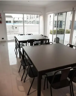 a group of tables and chairs in a room with windows at Apart France - Monoambiente con piscina y estacionamiento in Río Cuarto