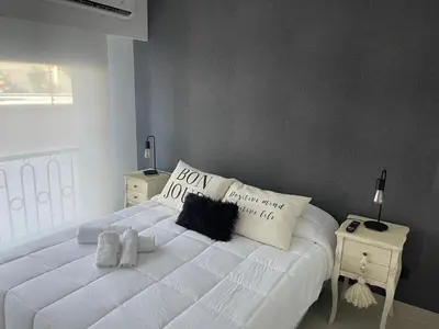 a bedroom with a white bed with pillows and a window at Apart France - Monoambiente con piscina y estacionamiento in Río Cuarto