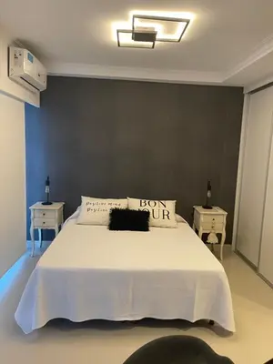 a bedroom with a large white bed with two night stands at Apart France - Monoambiente con piscina y estacionamiento in Río Cuarto