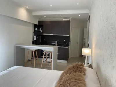 a bedroom with a bed and a kitchen with a table at Apart France - Monoambiente con piscina y estacionamiento in Río Cuarto