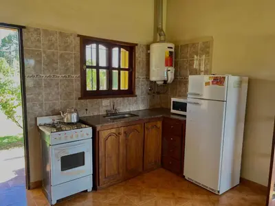 a kitchen with a white refrigerator and a stove at Cabañas Amore Mío in Mina Clavero