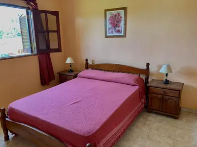 a bedroom with a bed with a red bedspread at Cabañas Amore Mío in Mina Clavero