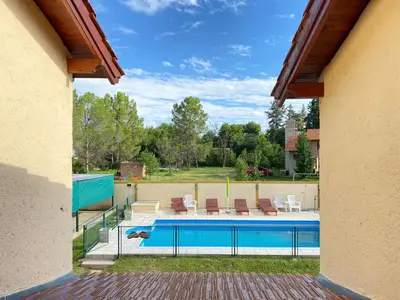 a swimming pool in a backyard with chairs at Cabañas Amore Mío in Mina Clavero
