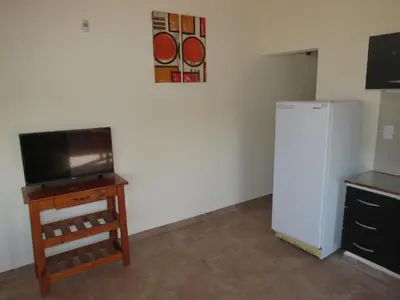 a kitchen with a refrigerator and a table and a counter at Cabañas Puentes Amarillos in Santa Rosa de Calamuchita