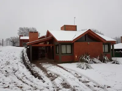 a house with a snow covered driveway in front of it at Cabañas Puentes Amarillos in Santa Rosa de Calamuchita