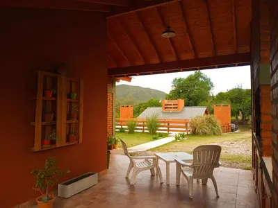 a patio with a table and chairs and a view of a yard at Cabañas Puentes Amarillos in Santa Rosa de Calamuchita