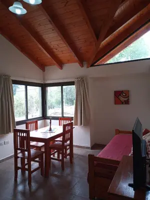 a dining room with a table and chairs and windows at Cabañas Puentes Amarillos in Santa Rosa de Calamuchita