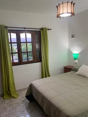 a bedroom with a bed and a window with green curtains at Abdulle Complejo Turistico Centro in Villa Cura Brochero