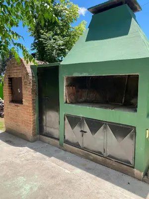 a green building with a gate and a brick wall at Abdulle Complejo Turistico Centro in Villa Cura Brochero