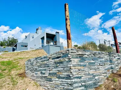 a stone retaining wall in front of a building at Depto en la Sierra!! Barrio Villa del Lago con vista a los Gigantes in Villa Carlos Paz