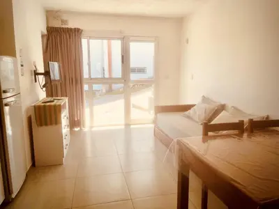 a room with a bed and a refrigerator and a window at Depto en la Sierra!! Barrio Villa del Lago con vista a los Gigantes in Villa Carlos Paz