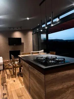 a kitchen with a stove and a living room at Cabaña La Alemana in Villa Berna