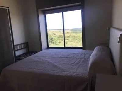 a bedroom with a bed and a large window at Cabaña La Alemana in Villa Berna