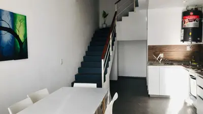 a kitchen with a staircase with a white table and chairs at Lofts en la Sierra!! Excelente vista a los Gigantes in Villa Carlos Paz