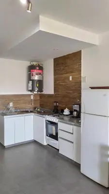 a kitchen with white cabinets and a white refrigerator at Lofts en la Sierra!! Excelente vista a los Gigantes in Villa Carlos Paz