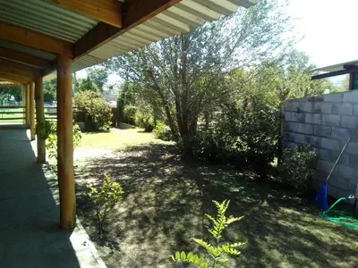 a shady patio under a wooden pergola at LUMALU Deptos in Villa Cura Brochero