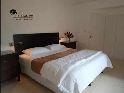 a bedroom with a large bed with white sheets at El Campo Departamentos in Merlo