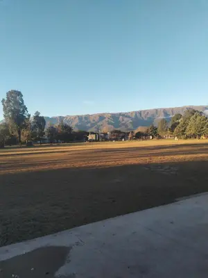 an empty field with trees and mountains in the background at El Campo Departamentos in Merlo
