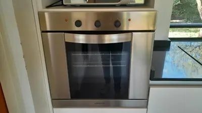 a stainless steel oven in a kitchen with a microwave at El Campo Departamentos in Merlo