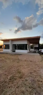 a large white house with a roof on a field at El Campo Departamentos in Merlo