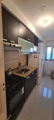 a kitchen with black cabinets and a stove and refrigerator at Departamento 1 dormitorio en complejo con amenities - Córdoba Ciudad in Cordoba