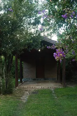 a brick building with a door and some trees at El jagüel in Villa General Belgrano