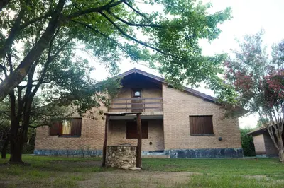 a large brick house with trees in front of it at El jagüel in Villa General Belgrano
