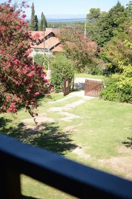 a view from a window of a yard with pink flowers at El jagüel in Villa General Belgrano
