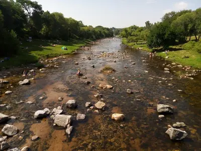 a river with rocks and people in the water at Alojamiento entre rios y montañas in Villa Carlos Paz