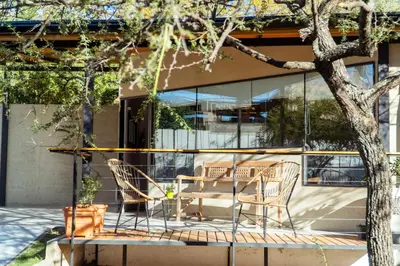 two chairs and a table in front of a building at Complejo Quiya - Departamento Los Espinillos con hidromasaje in Alta Gracia