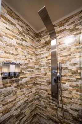 a shower in a bathroom with a stone wall at OMM Suites Resort, Villa General Belgrano in Villa General Belgrano