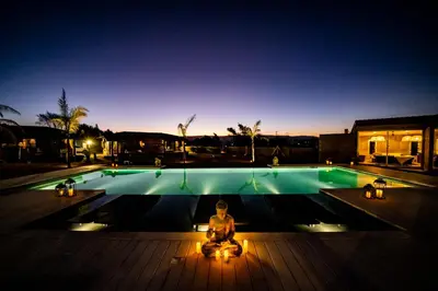 a woman sitting in meditation in front of a swimming pool at OMM Suites Resort, Villa General Belgrano in Villa General Belgrano