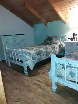 two beds in a room with blue walls and wooden floors at Lola Maria Apart in Villa General Belgrano
