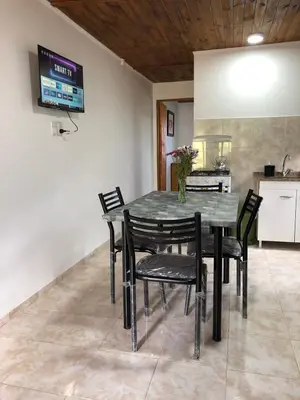 a dining room table with black chairs and a television at CABAÑAS FENIX con EL ARROYO AMBOY RODEANDO LA PROPIEDAD reservar con 24 hs de anticipación in Villa Amancay