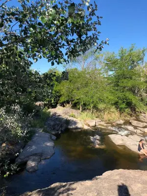 a stream of water with rocks and trees at CABAÑAS FENIX con EL ARROYO AMBOY RODEANDO LA PROPIEDAD reservar con 24 hs de anticipación in Villa Amancay
