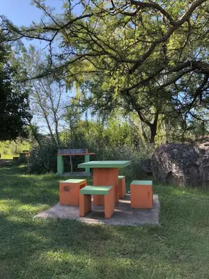 a picnic table and benches in a park at CABAÑAS FENIX con EL ARROYO AMBOY RODEANDO LA PROPIEDAD reservar con 24 hs de anticipación in Villa Amancay