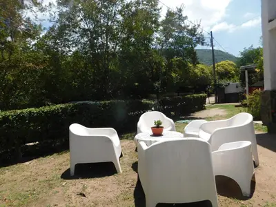 a group of white chairs and a table with a plant on it at Filipao Aparts in Santa Rosa de Calamuchita