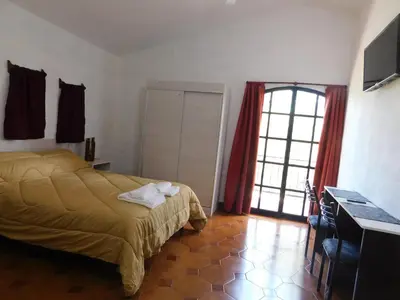 a bedroom with a bed and a desk and a window at Filipao Aparts in Santa Rosa de Calamuchita