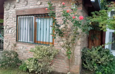a brick building with a window with roses at Cabañas Farah Estancia Vieja ideal para 2 a 3 huéspedes in Villa Carlos Paz