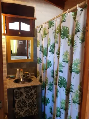 a bathroom with a shower curtain with a sink at Cabañas Farah Estancia Vieja ideal para 2 a 3 huéspedes in Villa Carlos Paz