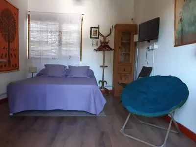 a bedroom with a blue bed and a television at Cabañas Farah Estancia Vieja ideal para 2 a 3 huéspedes in Villa Carlos Paz